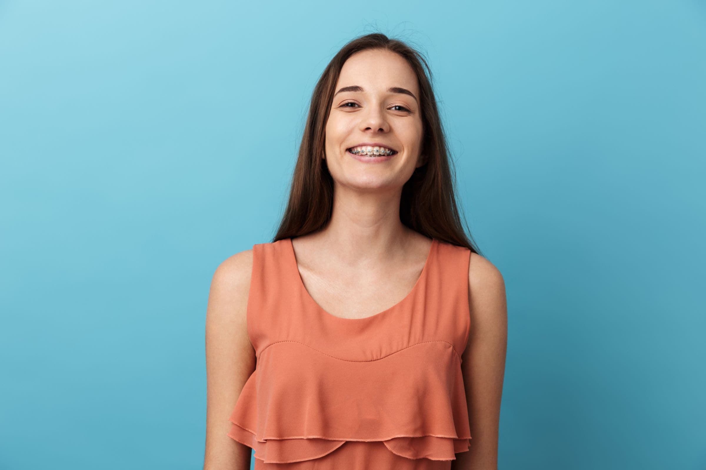 Smiling young woman wearing braces, showcasing supportive orthodontic care in Tigard.